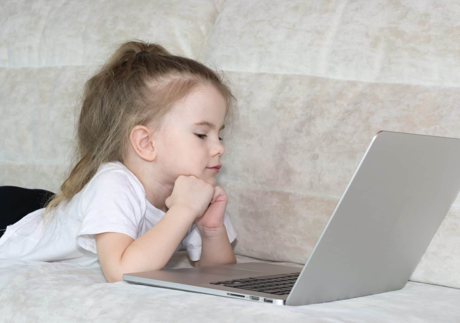 girl in white t-shirt using silver laptop computer